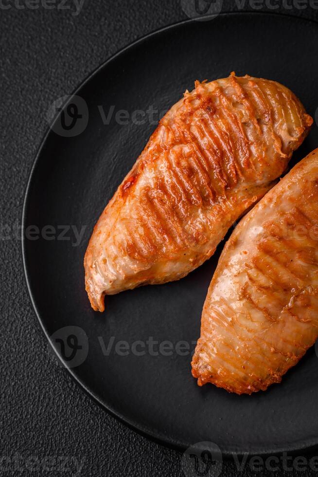 Delicious fresh grilled chicken fillet with spices and herbs on a dark concrete background photo