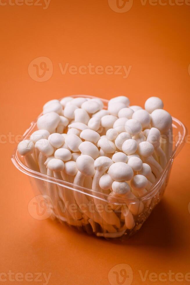 Small white edible beech mushrooms with salt and spices on a plain background photo