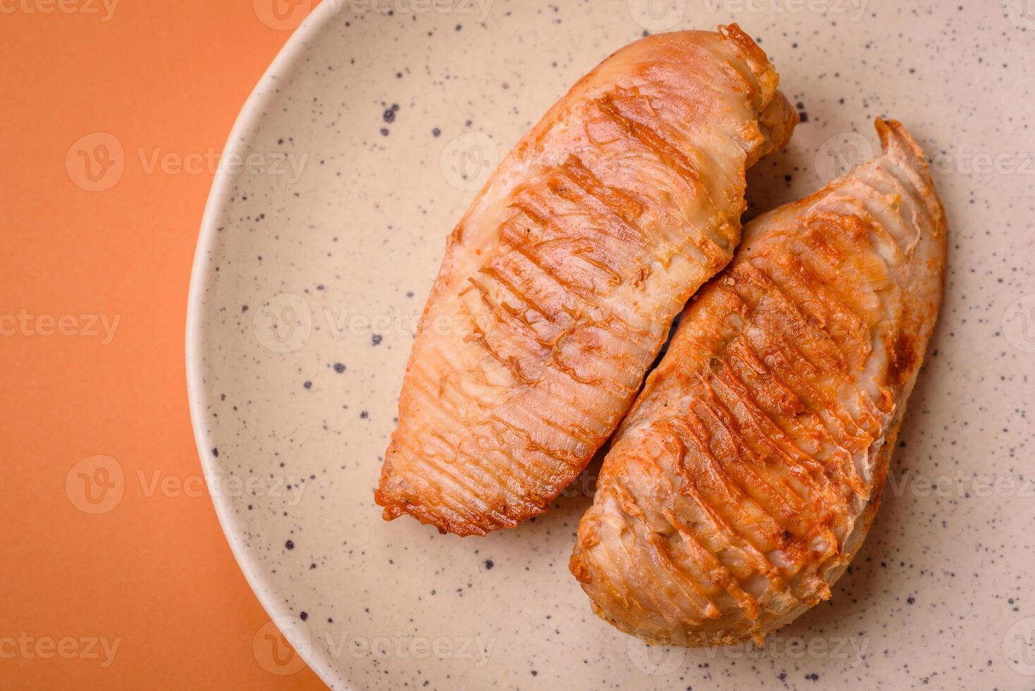 Delicious fresh grilled chicken fillet with spices and herbs on a dark concrete background photo