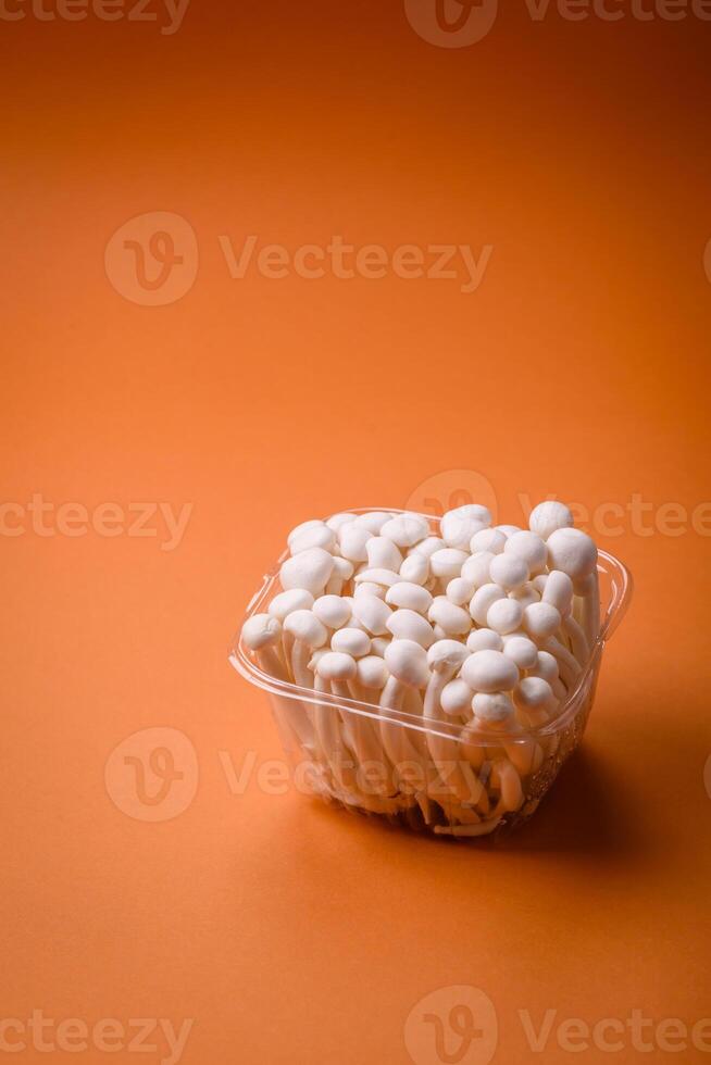 Small white edible beech mushrooms with salt and spices on a plain background photo