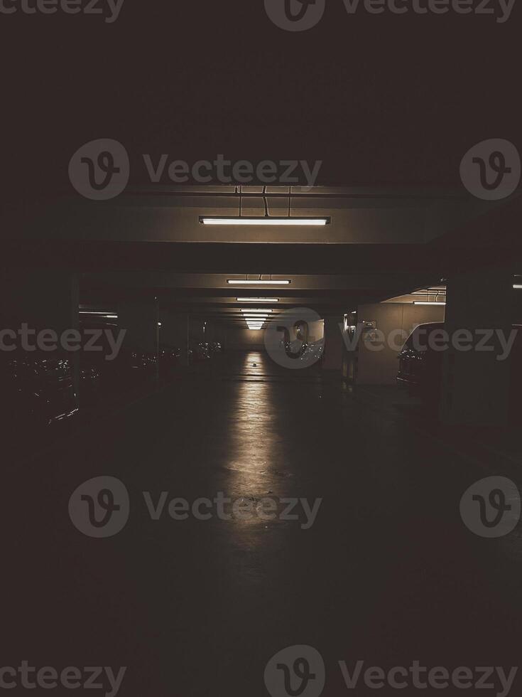 The dimly lit empty parking garage exudes a grunge atmosphere with its worn-out asphalt. photo