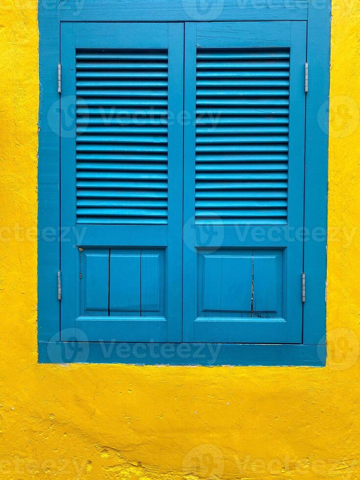 Blue window isolated  on the background of a yellow ragged wall. photo