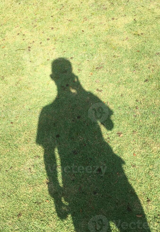 A shadow in the form of a human body with grass texture background photo