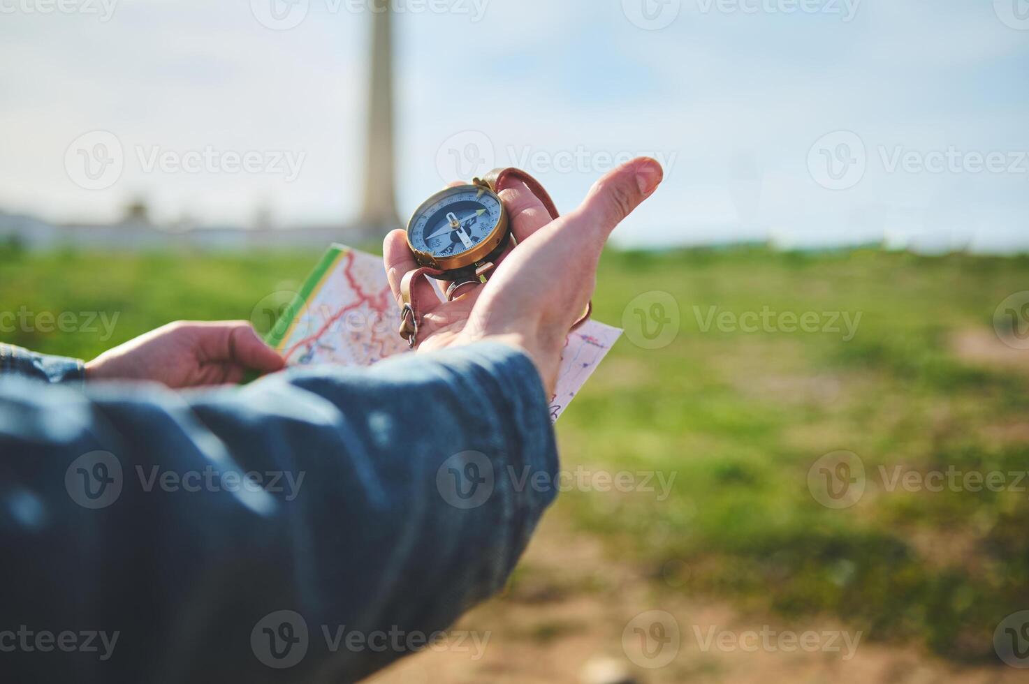 Close-up hands of a male hiker tourist traveler looking for directions with a compass, standing on the beach photo