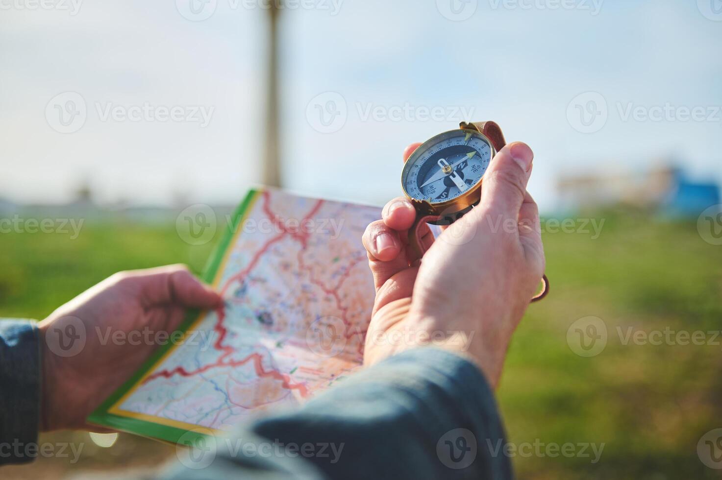 Male hand holds compass with magnetic arrow showing north direction, over a map while discovers a new travel destination photo