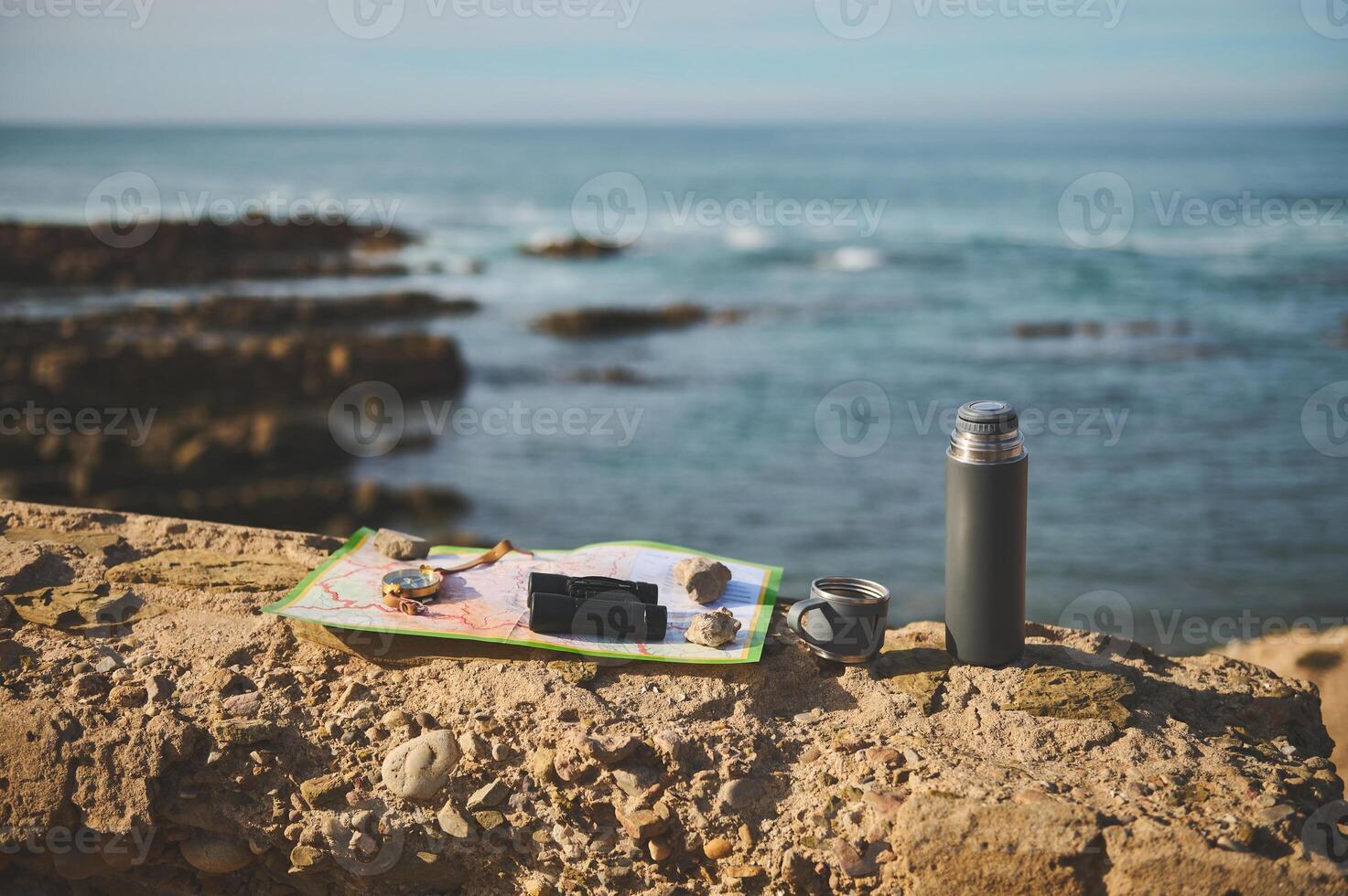 Still life with navigational equipment and thermos flask on the cliff against Atlantic ocean background photo