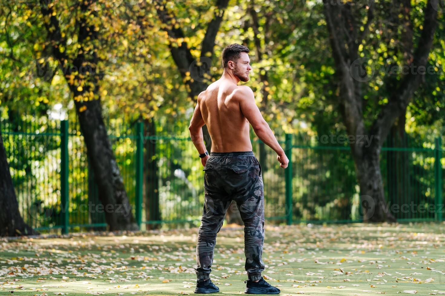 A Fit Tennis Player on the Court. A shirtless man standing on a tennis court photo