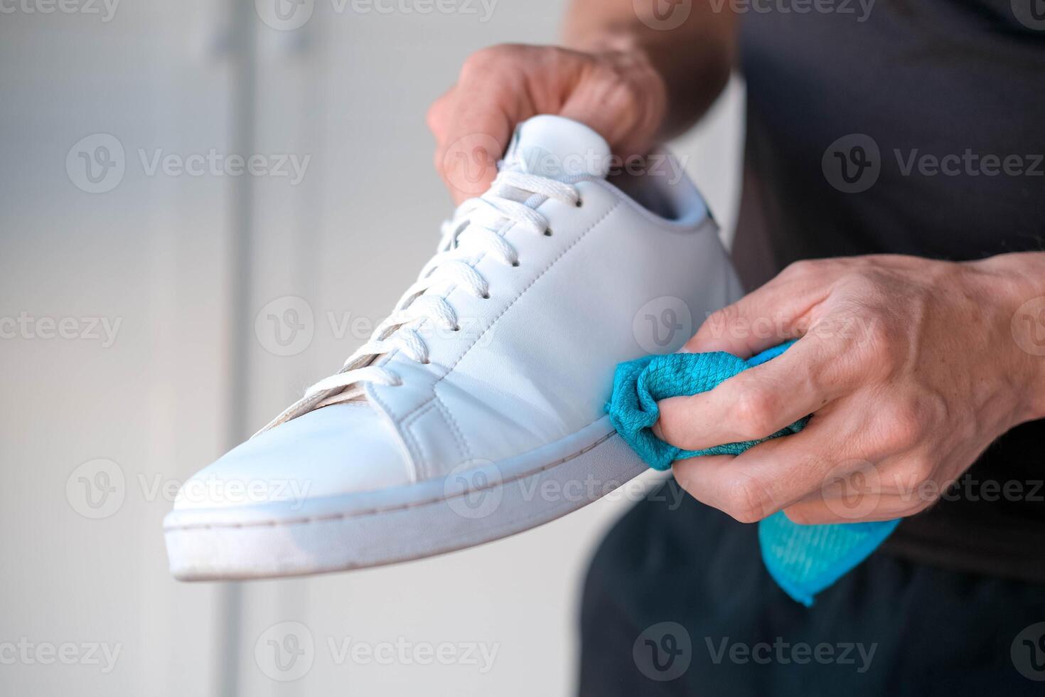 un hombre limpia blanco zapatillas desde suciedad foto