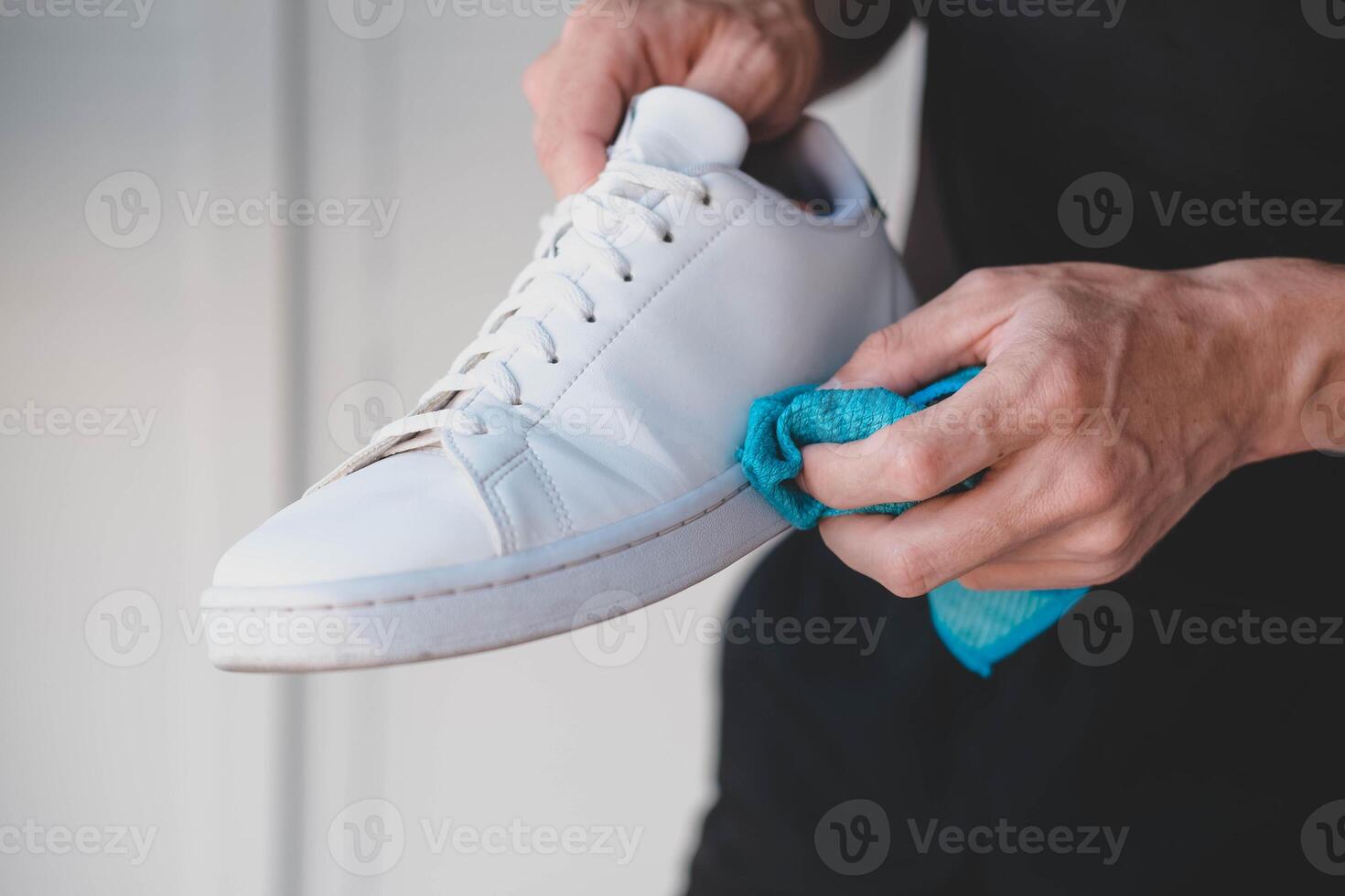 un hombre limpia blanco zapatillas desde suciedad foto