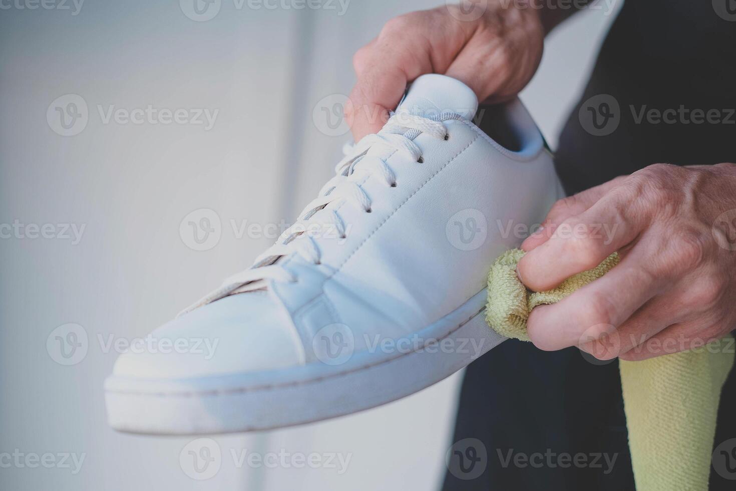 A man cleans white sneakers from dirt photo