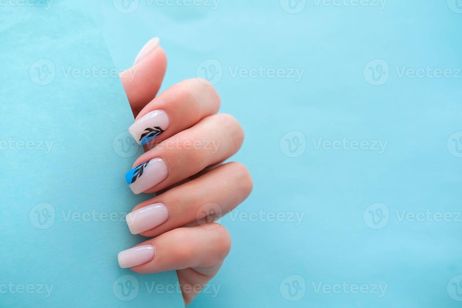 Beautiful female hands with manicure on a blue background. Stylish nail design. Summer manicure with a blue pattern on the nails. Copy space. photo