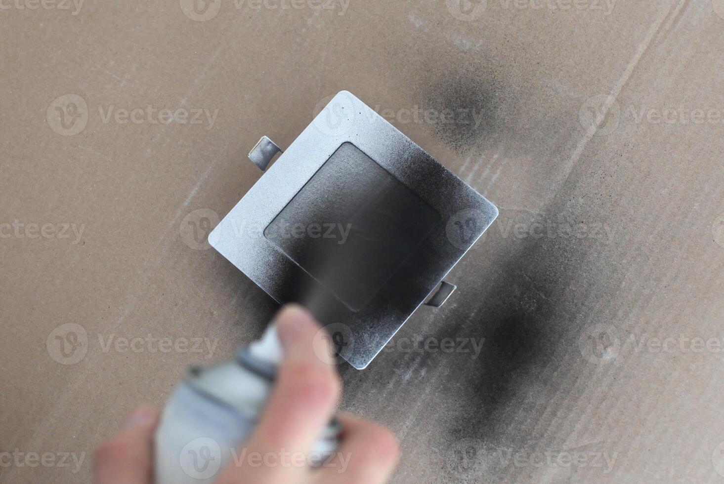 Step by step instructions for changing the color of the LED lamp. Male hands paint a lamp black with spray paint. Step 5 photo