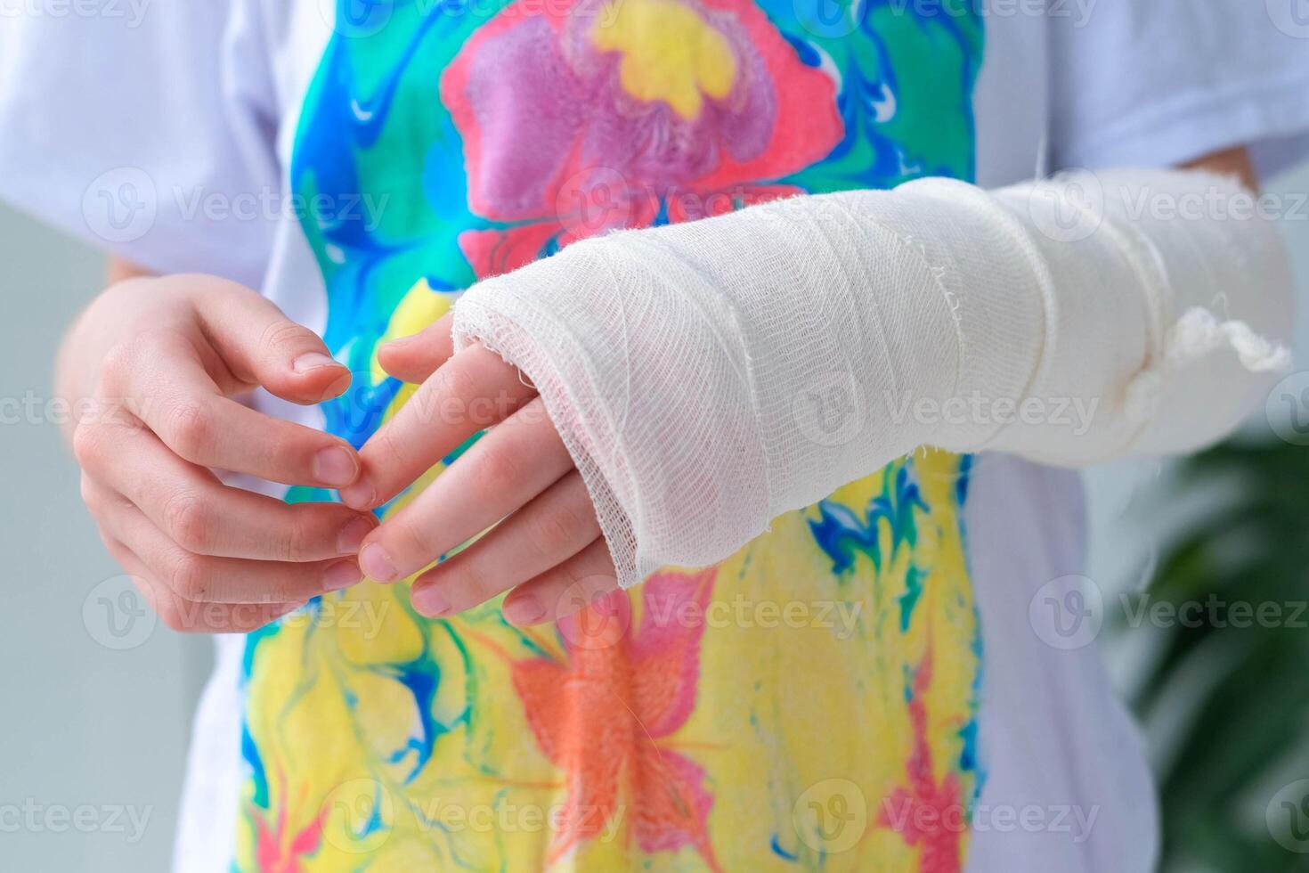 Close-up of a broken arm of a child in a cast. The girl holds her hand bent photo