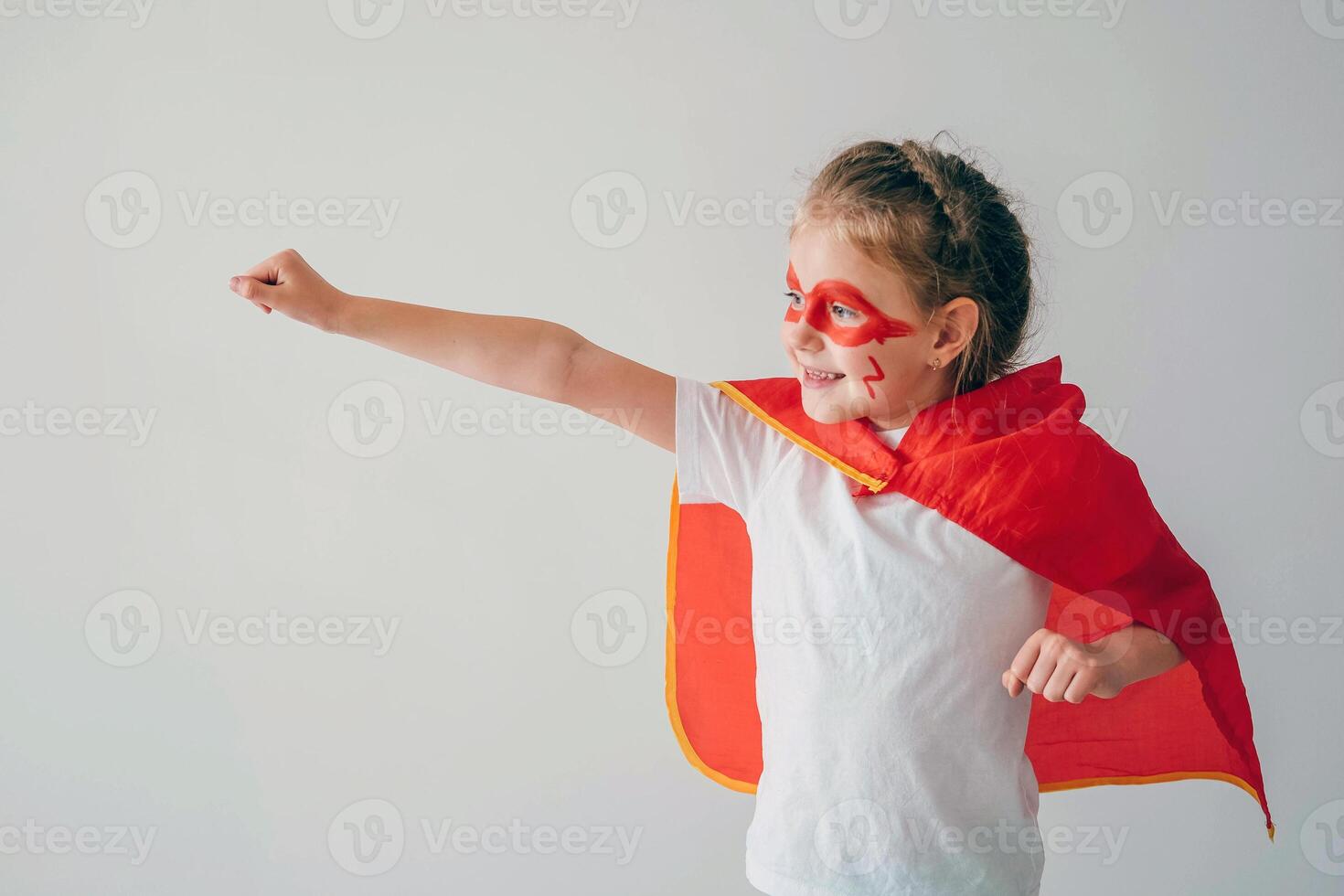 Funny little super hero girl in a red cloak. Superhero concept. Little child playing hero in the kids photo