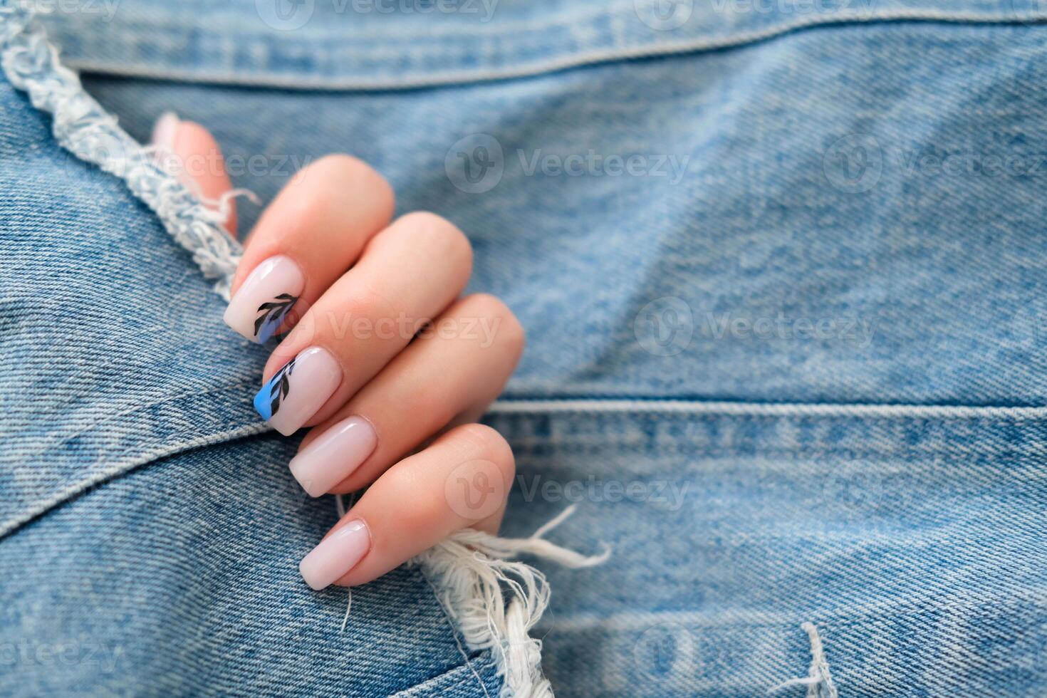 Beautiful female hands with manicure on a denim background. Stylish nail design. Summer manicure with a blue pattern on the nails. Copy space. photo
