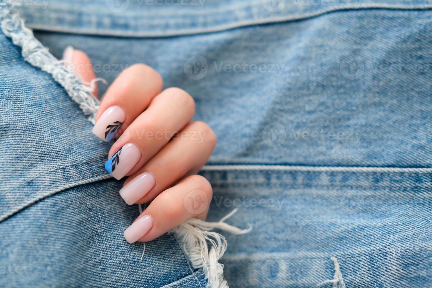 hermosa hembra manos con manicura en un mezclilla antecedentes. elegante uña diseño. verano manicura con un azul modelo en el clavos. Copiar espacio. foto