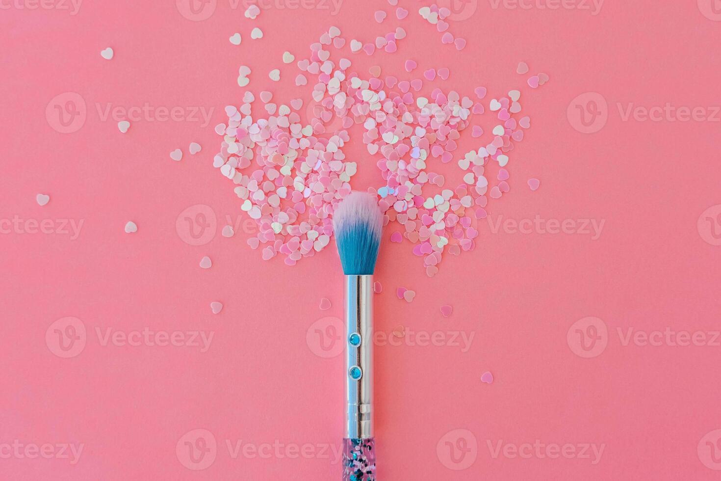 Makeup brush and shiny pink sequins on a pink background. Festive magic makeup concept. Template for design, top view Flat Lay Copy space. photo