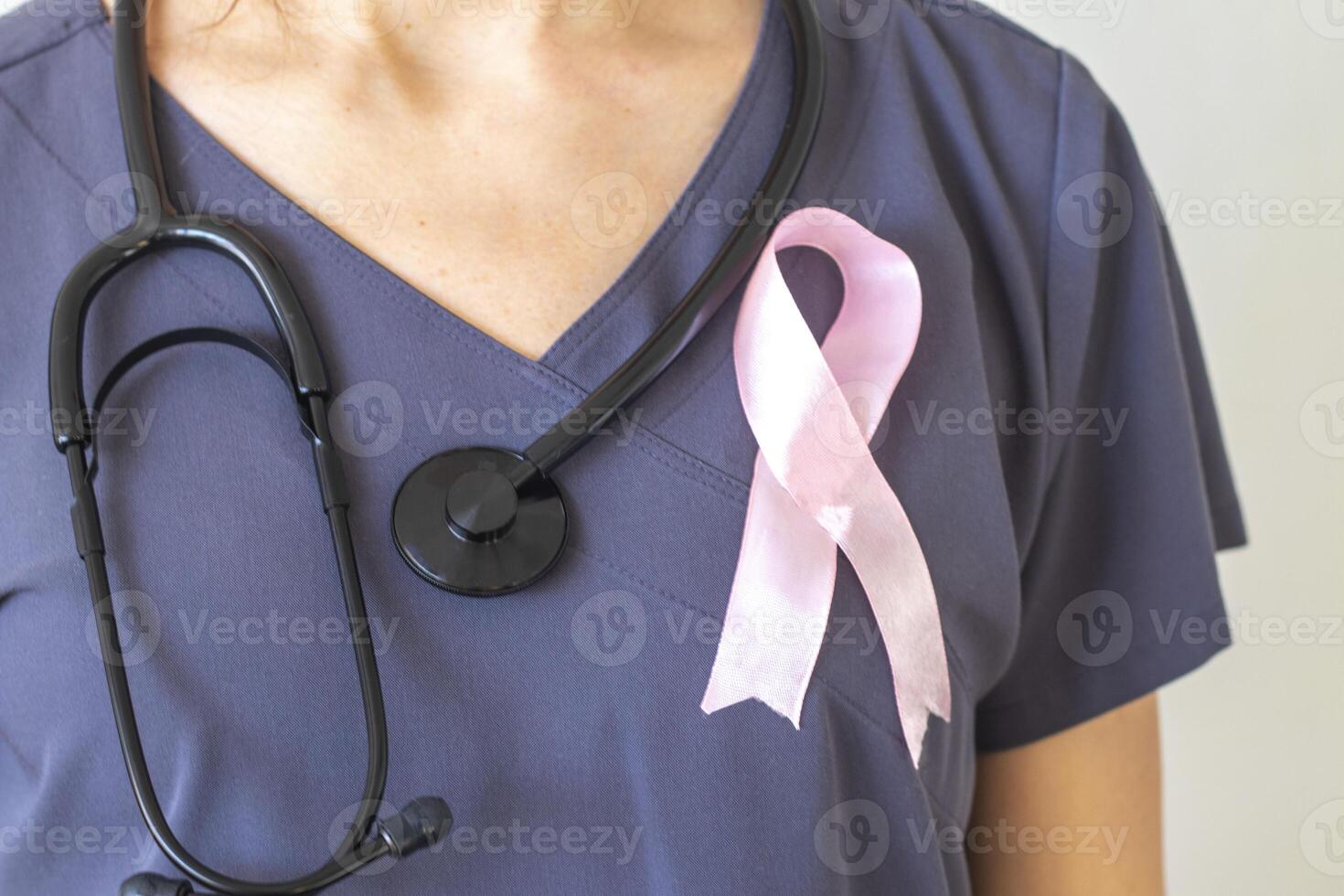 Disparo de el hembra médico en contra el blanco pared con rosado cinta, como un símbolo de un pecho cáncer conciencia. concepto foto