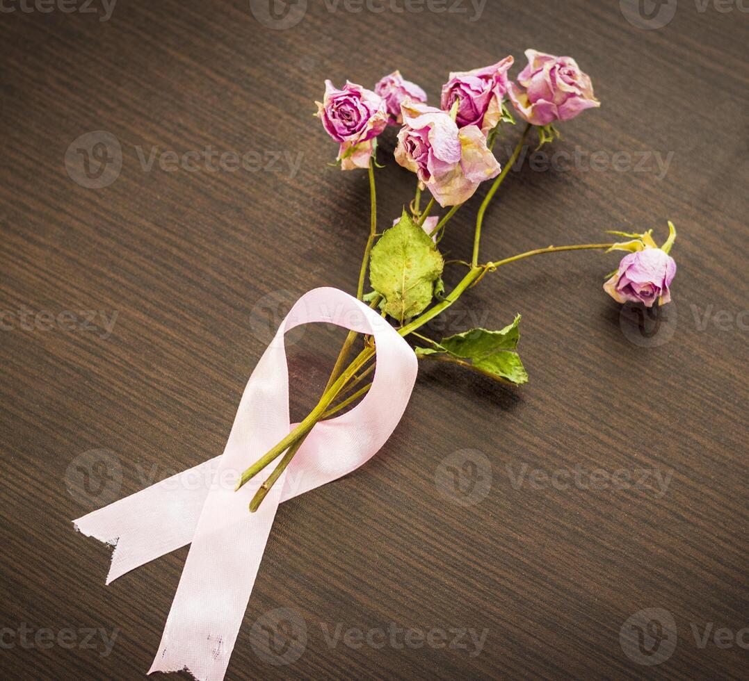 Shot of the dry roses wrapped in the pink ribbon, symbol of the breast cancer awareness. Concept photo