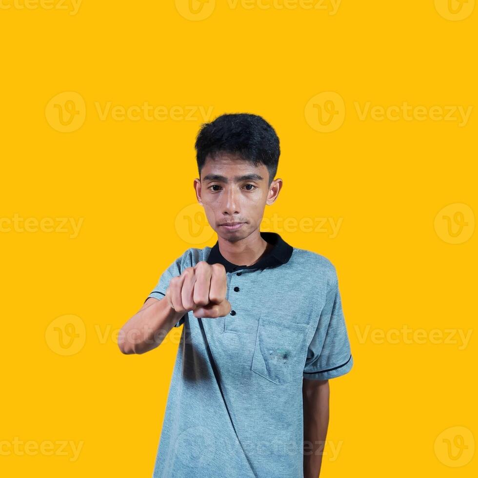 The enthusiastic face of the Asian youth clenched his fists. isolated on yellow background. photo