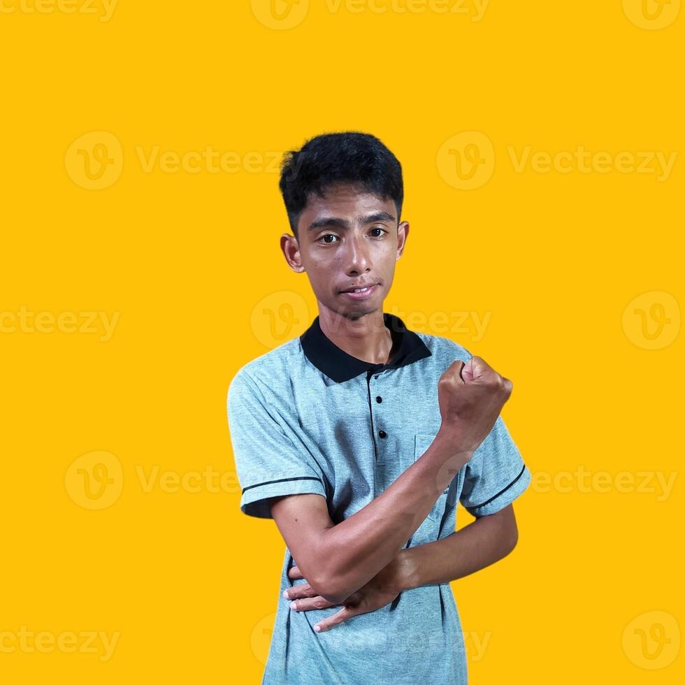 The enthusiastic face of the Asian youth clenched his fists. isolated on yellow background. photo