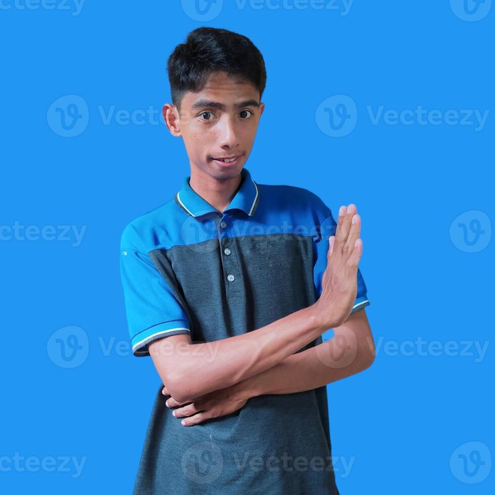 young asian man hands stop. with a serious face wearing a blue t-shirt, isolated on a blue background photo