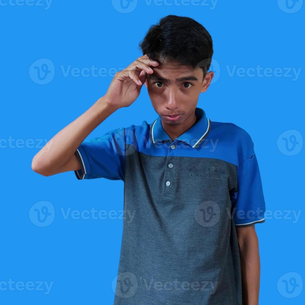 Confused Asian young man blue t-shirt, isolated blue background photo