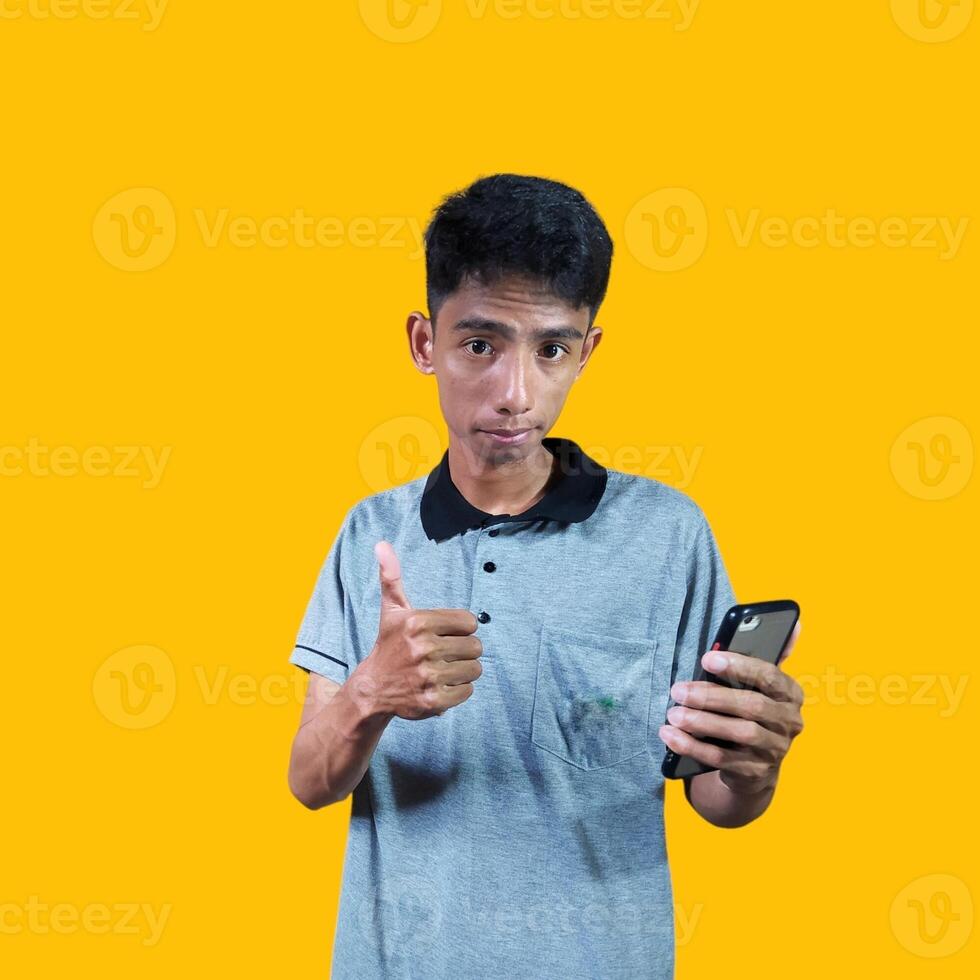 Asian man smiling face with okay gesture holding smart phone, isolated on blue background photo