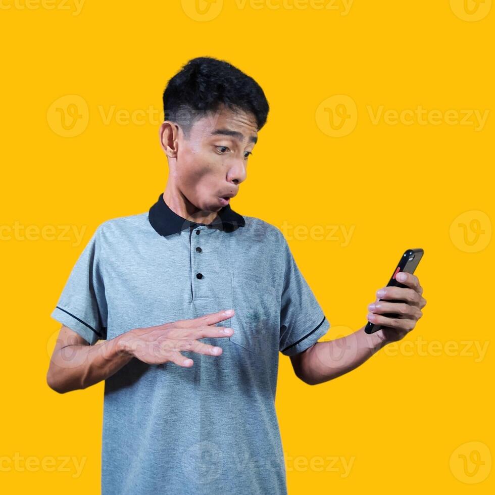 sorprendido cara de joven asiático hombre señalando a el vacío fotocopia espacio con un sorprendido rostro, vistiendo un gris foto