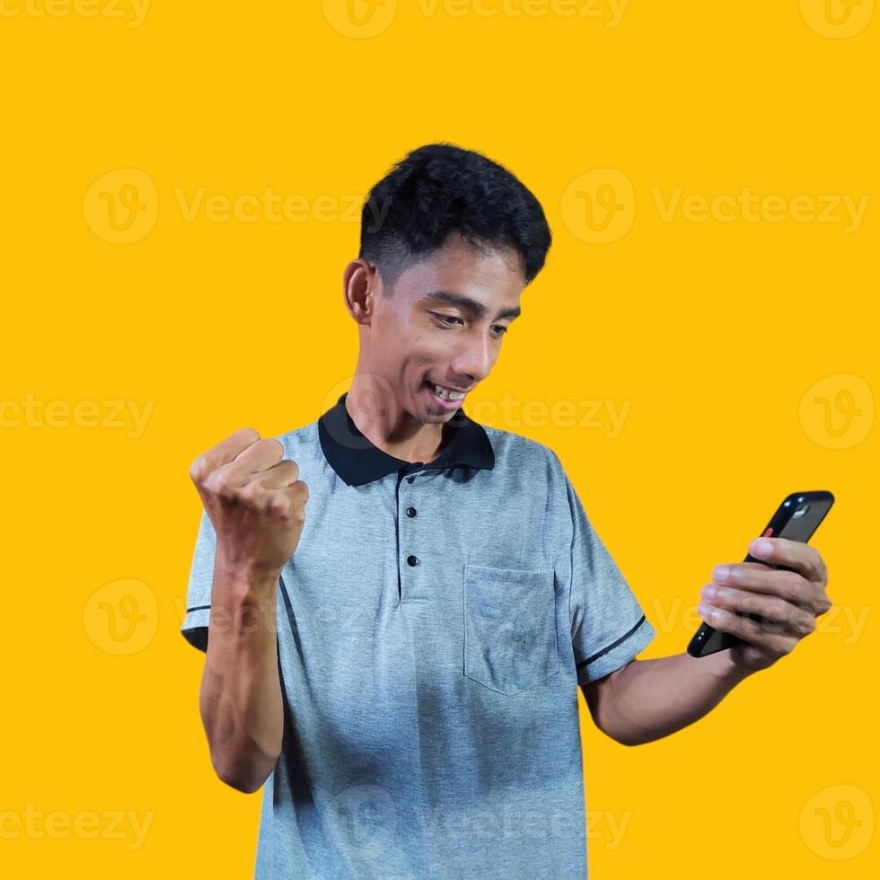 The enthusiastic face of the Asian youth clenched his fists. isolated on yellow background. photo