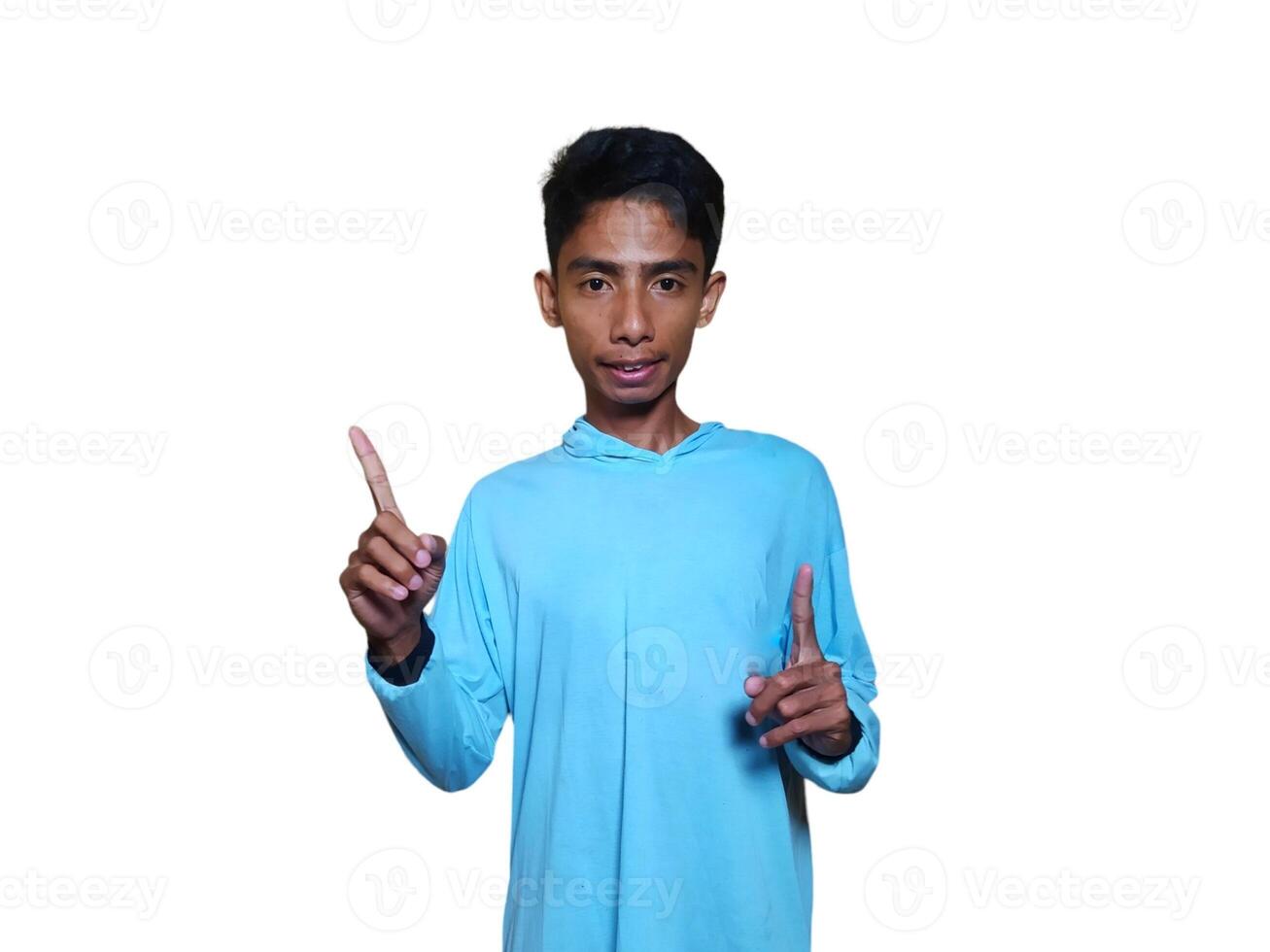 excited asian man wearing blue t-shirt pointing to the copy space on the side, isolated white background. photo