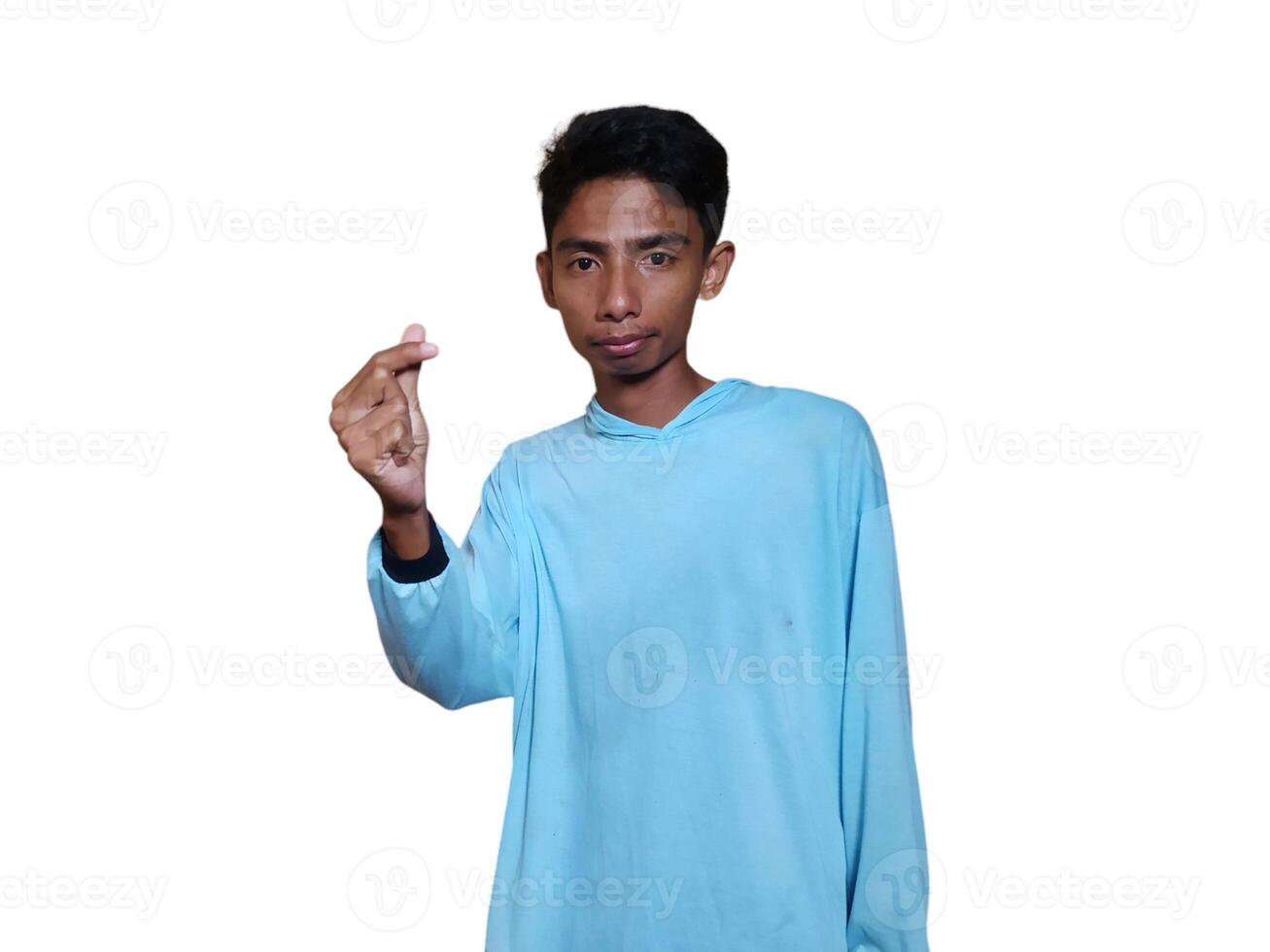 Young Asian man feeling happy and romantic forming heart gesture, wearing blue t-shirt on white background. photo