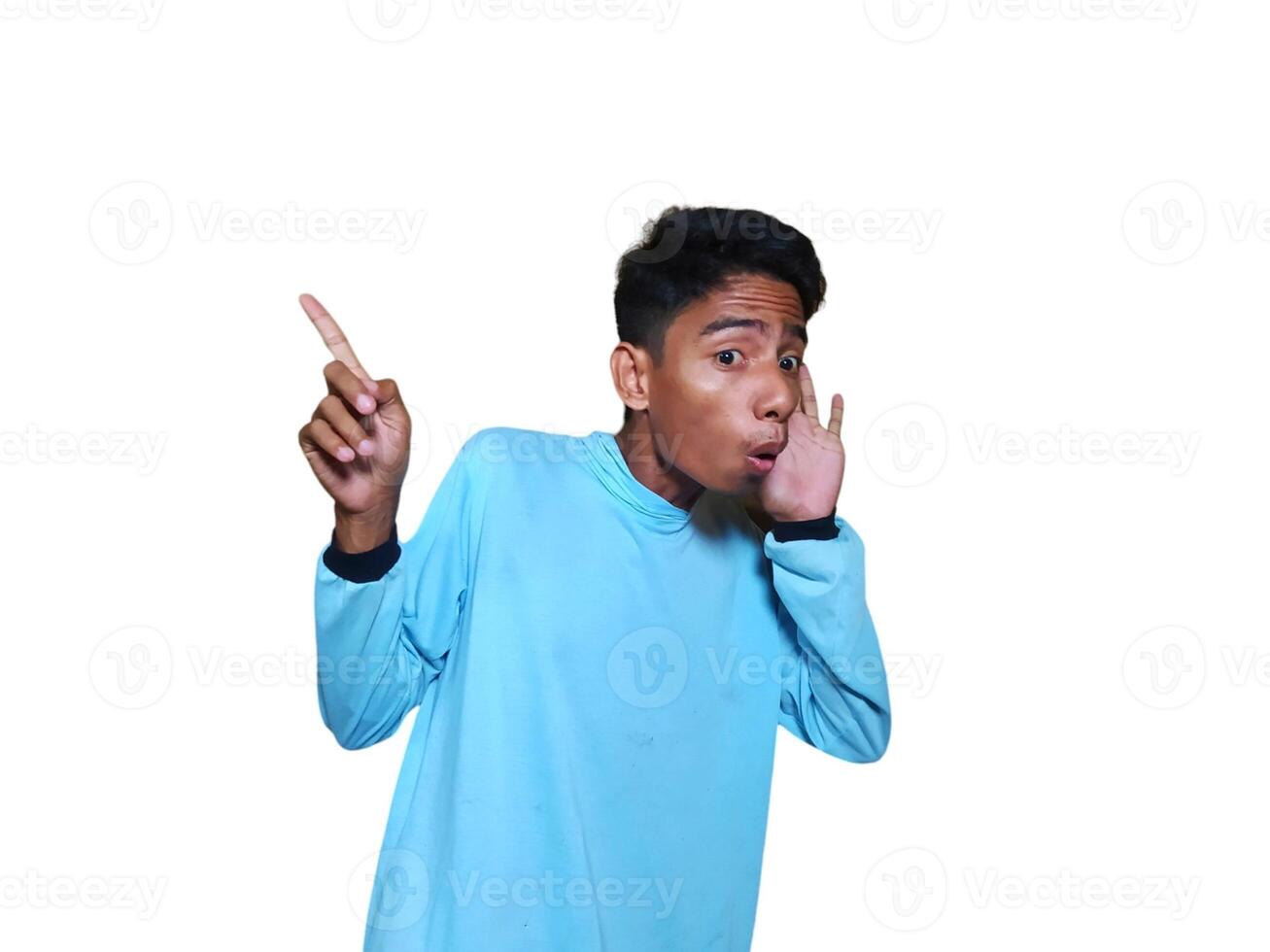 excited asian man wearing blue t-shirt pointing to the copy space on the side, isolated white background. photo