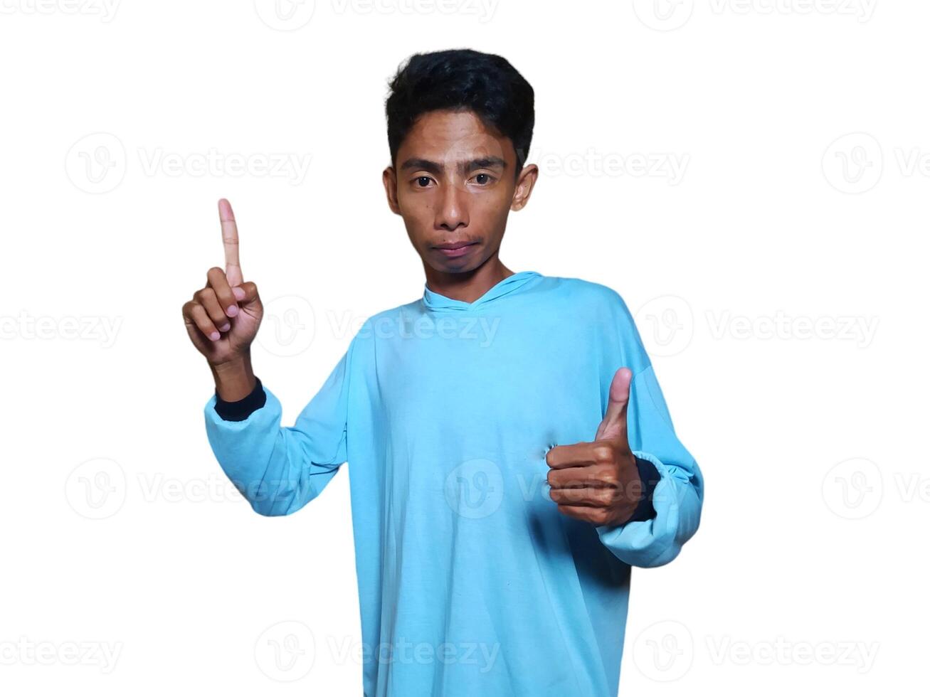 excited asian man wearing blue t-shirt pointing to the copy space on the side, isolated white background. photo