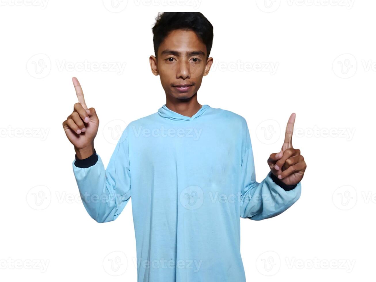 excited asian man wearing blue t-shirt pointing to the copy space on the side, isolated white background. photo