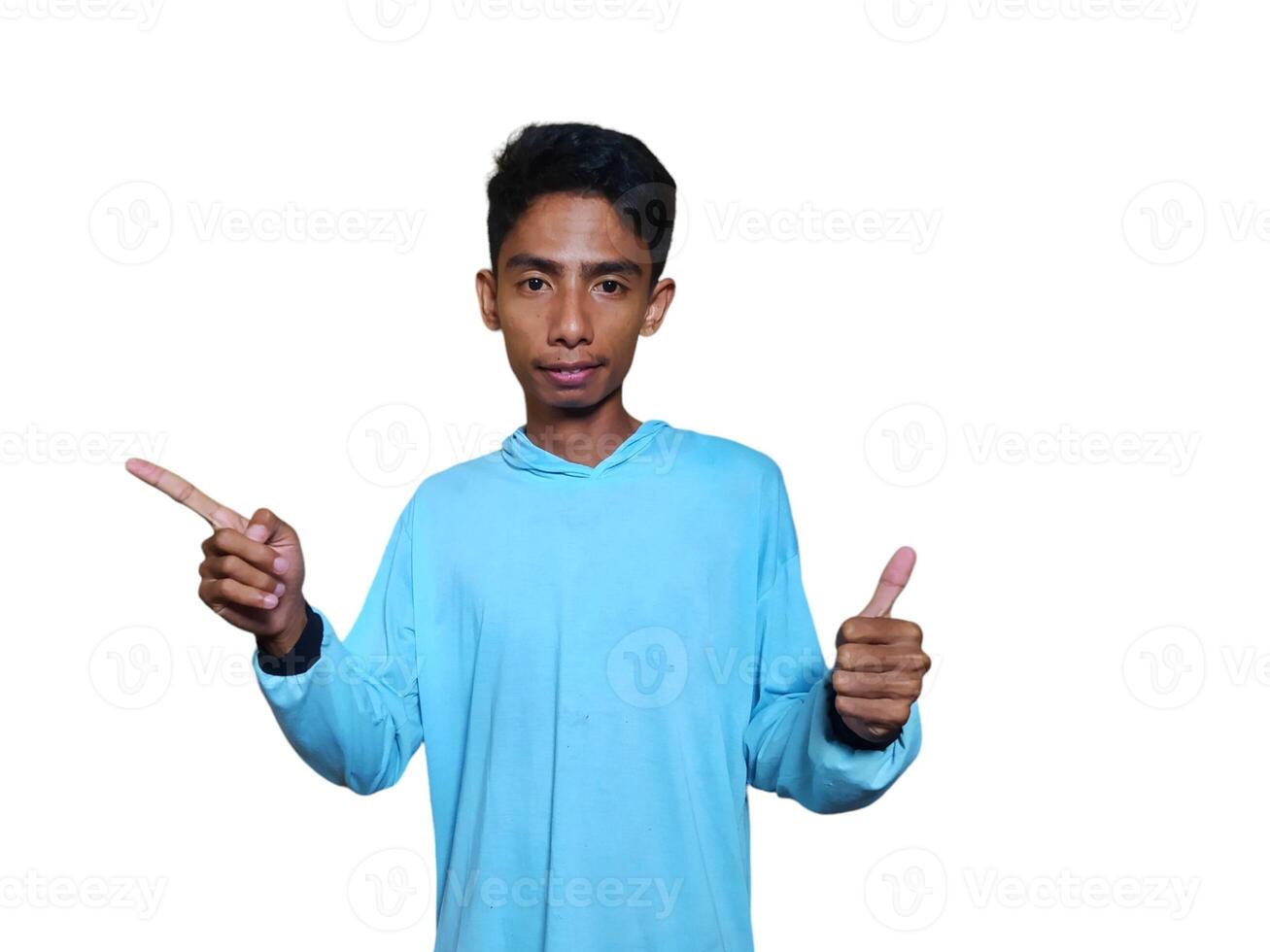 excited asian man wearing blue t-shirt pointing to the copy space on the side, isolated white background. photo