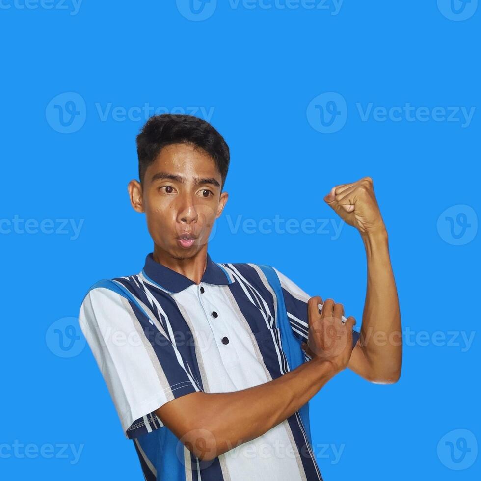 Excited Asian man wearing colorful t-shirt showing strong movement raising arms blue background. photo