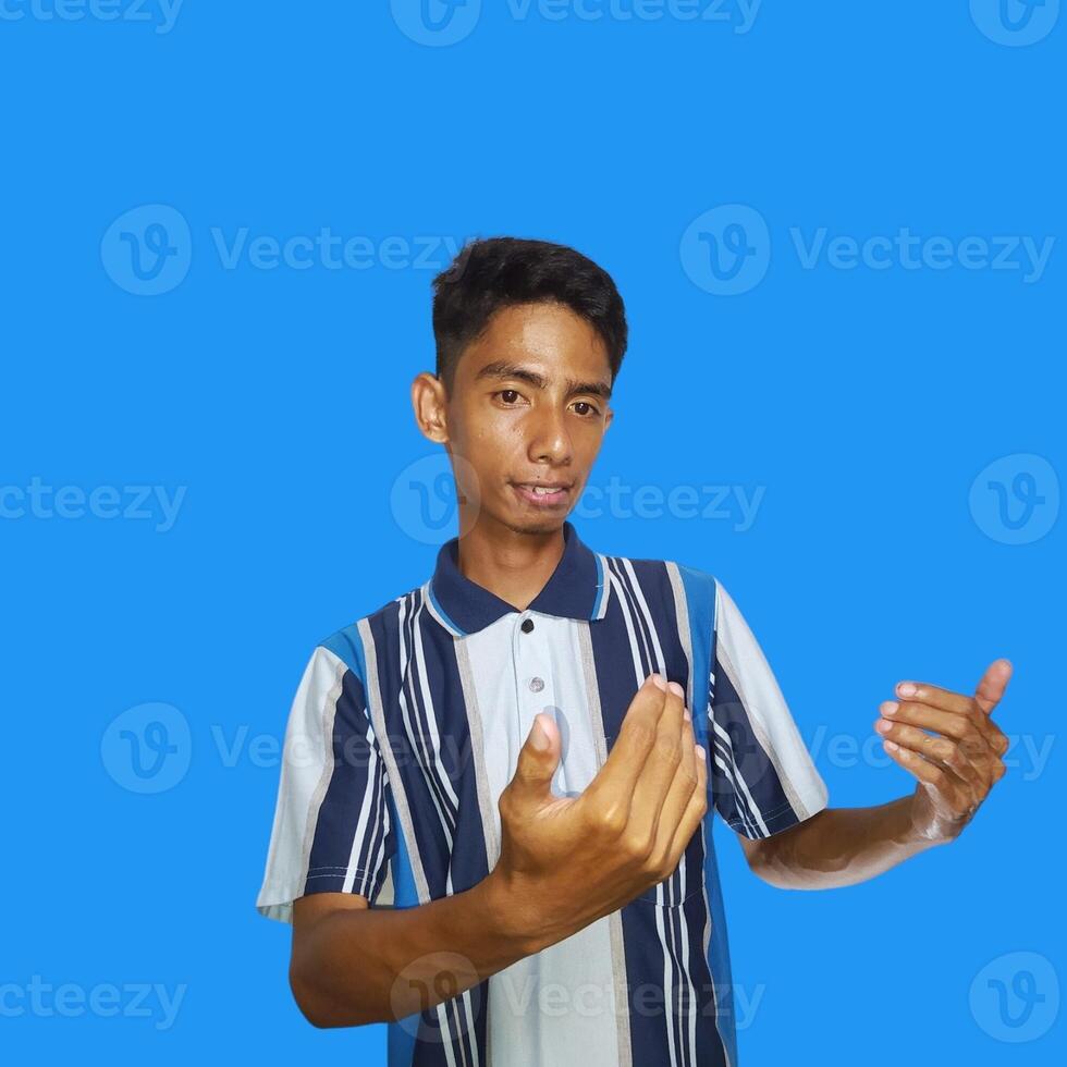 Young Asian man isolated on blue background inviting come with hands glad you came photo