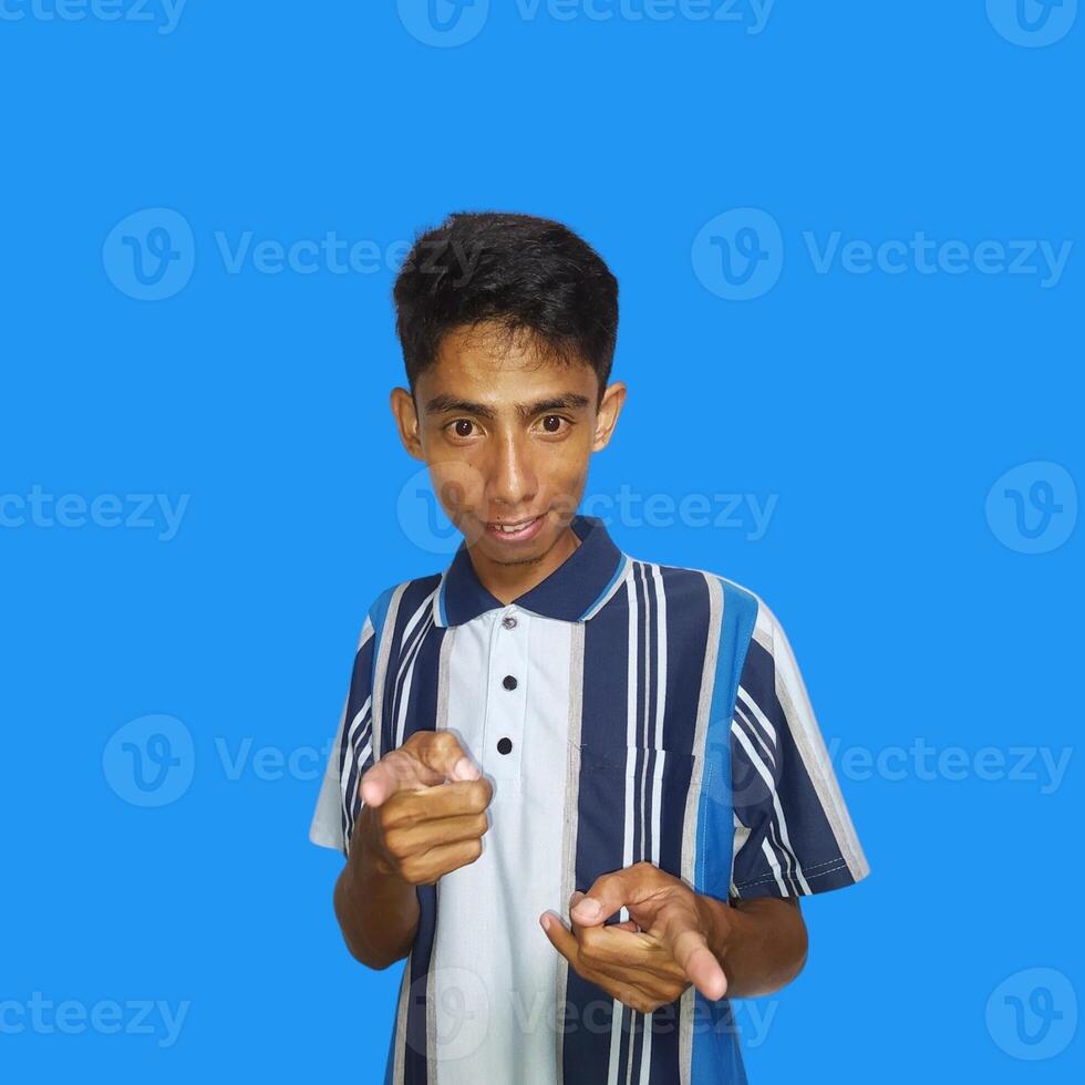 Young Asian man pointing at the camera with index finger, blue background. photo