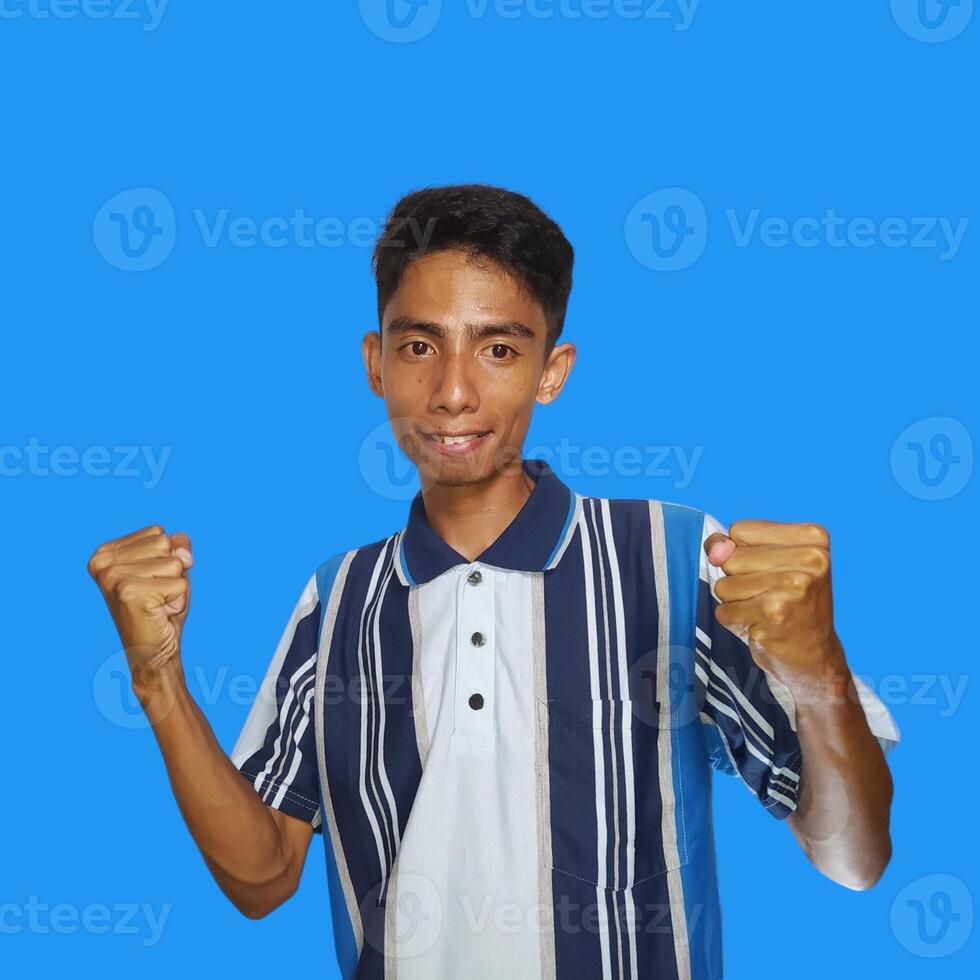 The enthusiastic face of the Asian youth clenched his fists. isolated on blue background. photo