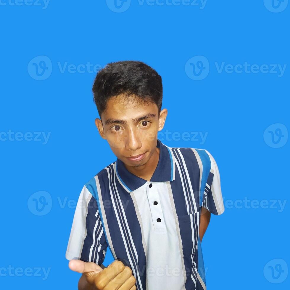 Young Asian man pointing at the camera with index finger, blue background. photo