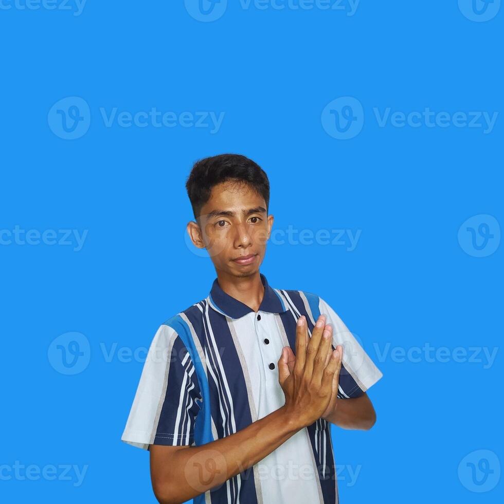 Young smiling asian man gesturing traditional gesture isolated on blue background. photo