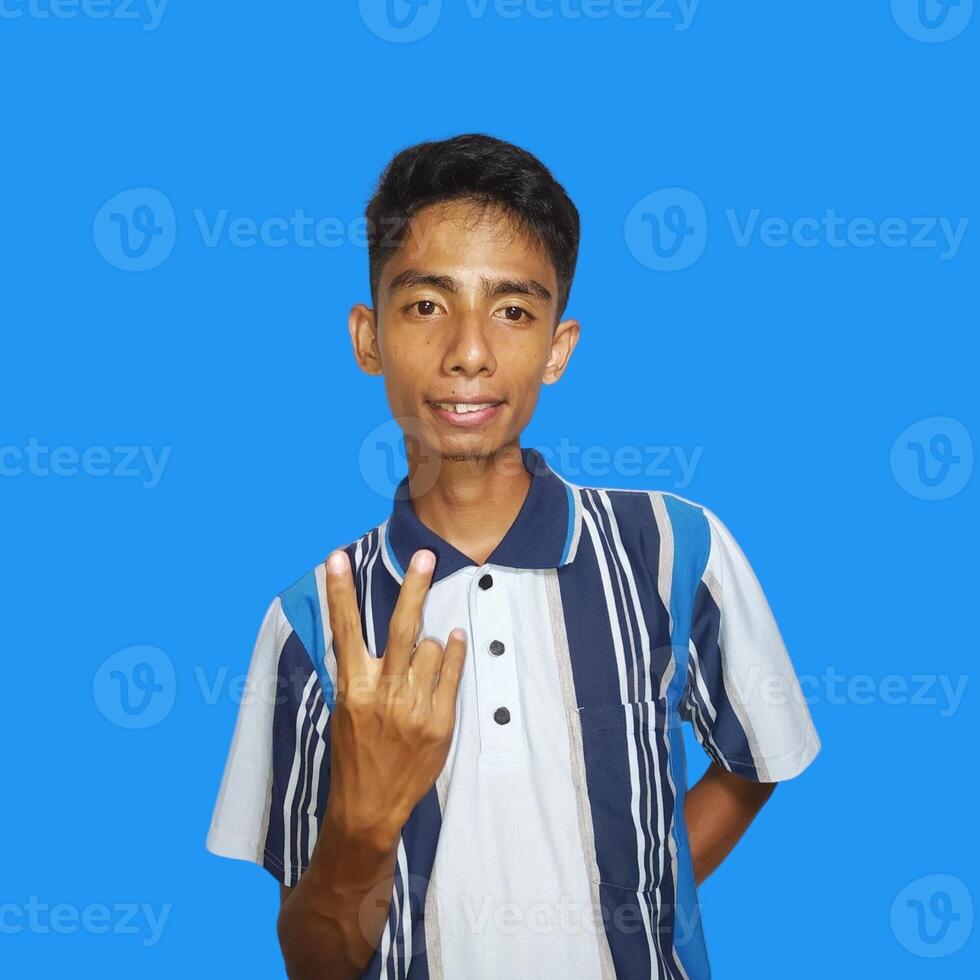 Outward looking young Asian man wearing colorful t-shirt, copy space index finger with new idea, isolated on blue background photo