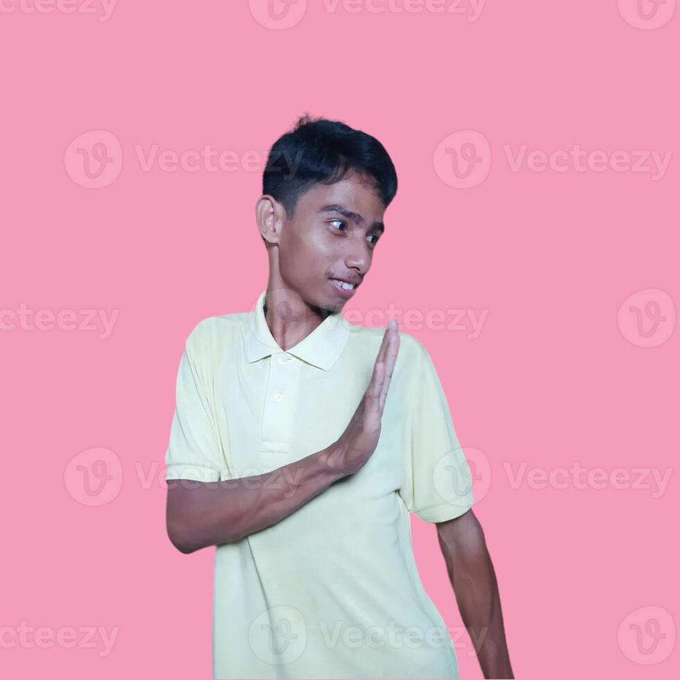 young asian man hands stop. with a serious face wearing a yellow t-shirt, isolated on a pink background photo