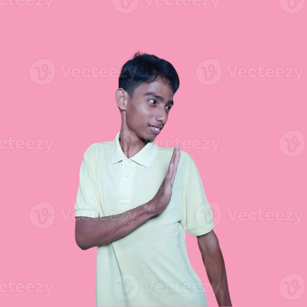 young asian man hands stop. with a serious face wearing a yellow t-shirt, isolated on a pink background photo