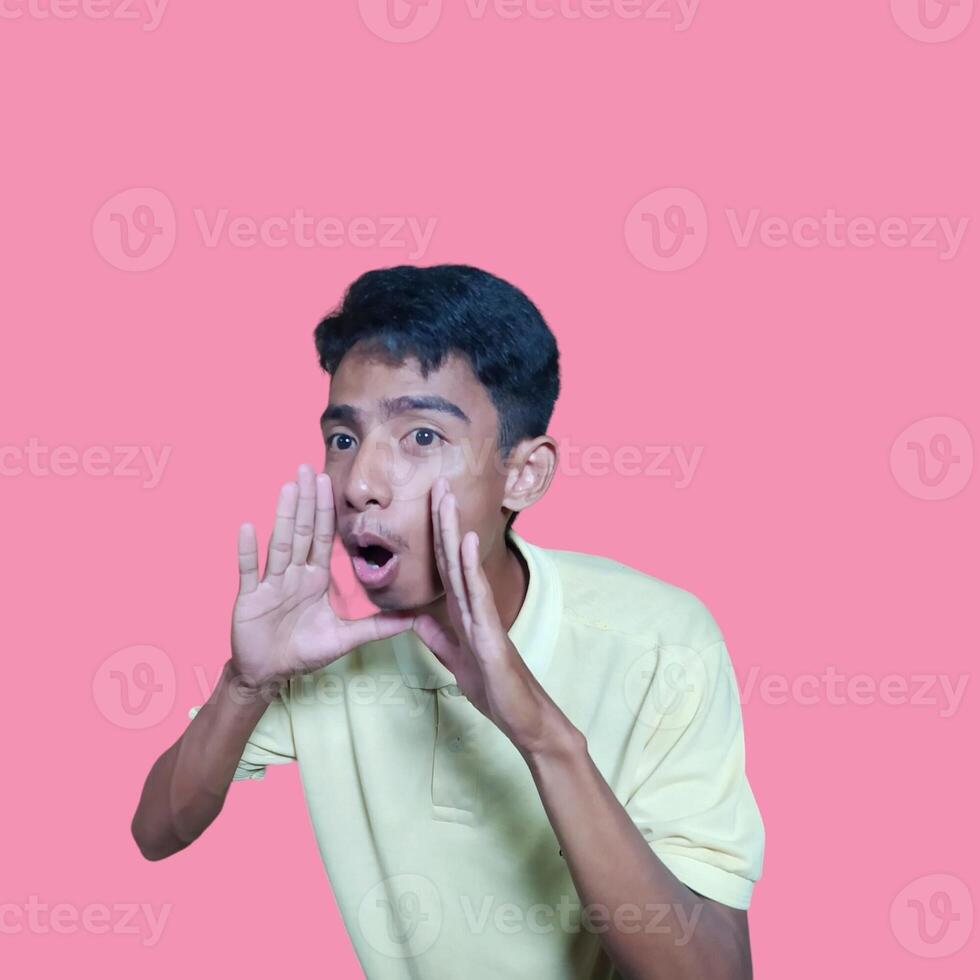 asian man shouting wearing yellow t-shirt, isolated pink background. photo