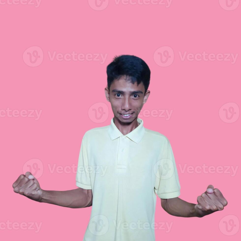 The enthusiastic face of the Asian youth clenched his fists. isolated on pink background. photo