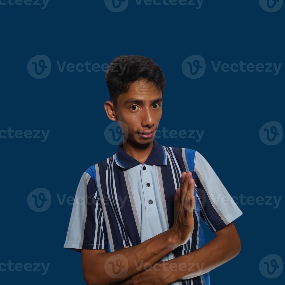 young asian man hands stop. with a serious face wearing a colorful t-shirt, isolated on a blue background photo