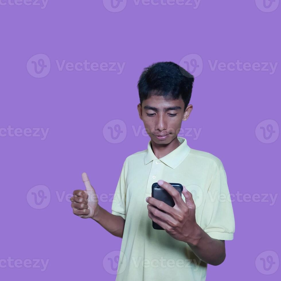 Asian man smiling face with okay gesture while holding smart phone, isolated on purple background photo