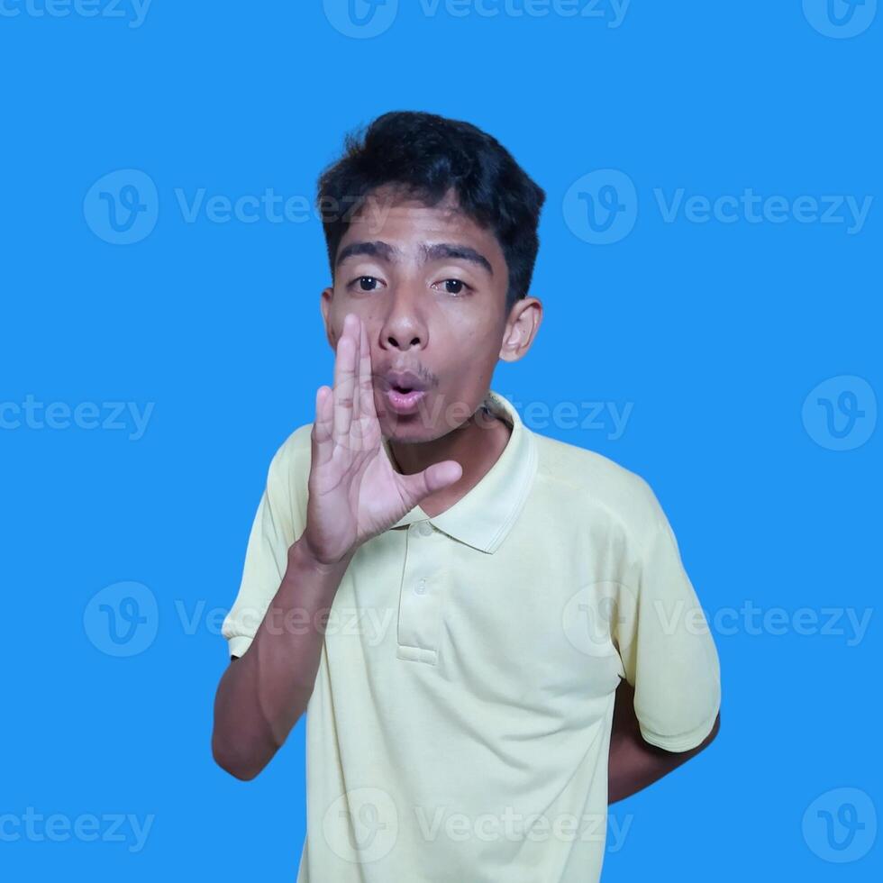 asian man shouting wearing yellow t-shirt, isolated blue background. photo